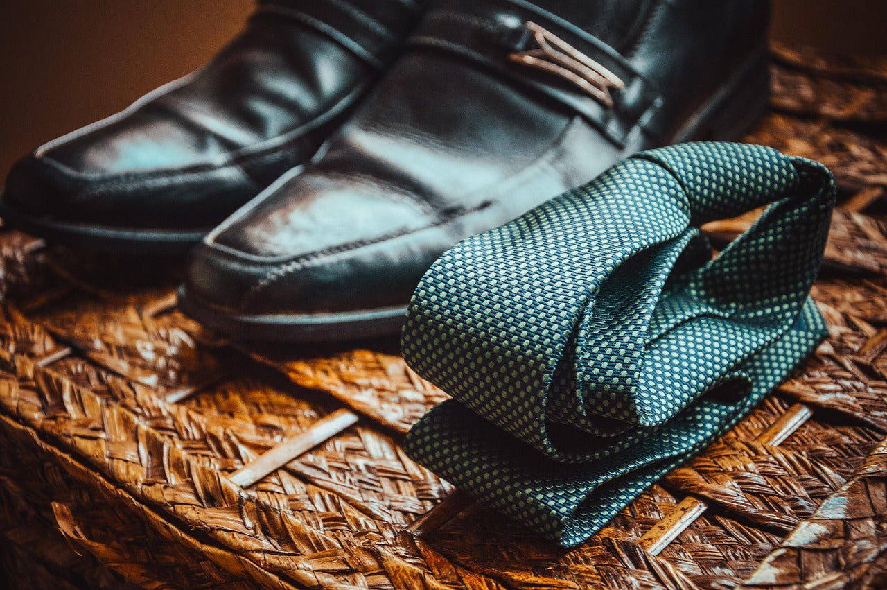 "Elegant black leather men’s dress shoes paired with a green patterned silk tie, presented as part of the men’s bestsellers collection."